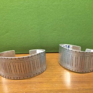 Two SIlver Color Bracelets Pair on a Wooden Surface