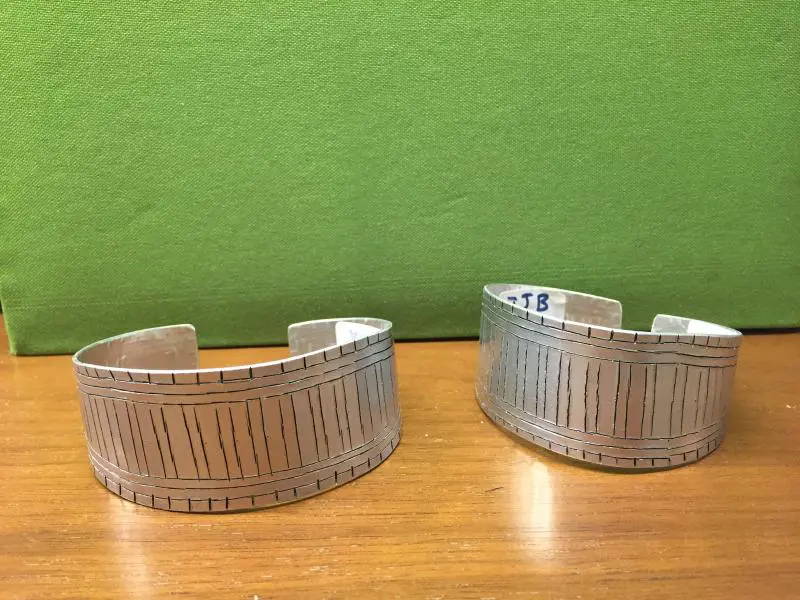 Two SIlver Color Bracelets Pair on a Wooden Surface