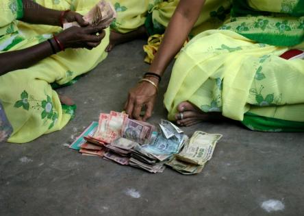 Bundles of money on the floor in front of a group of artisans