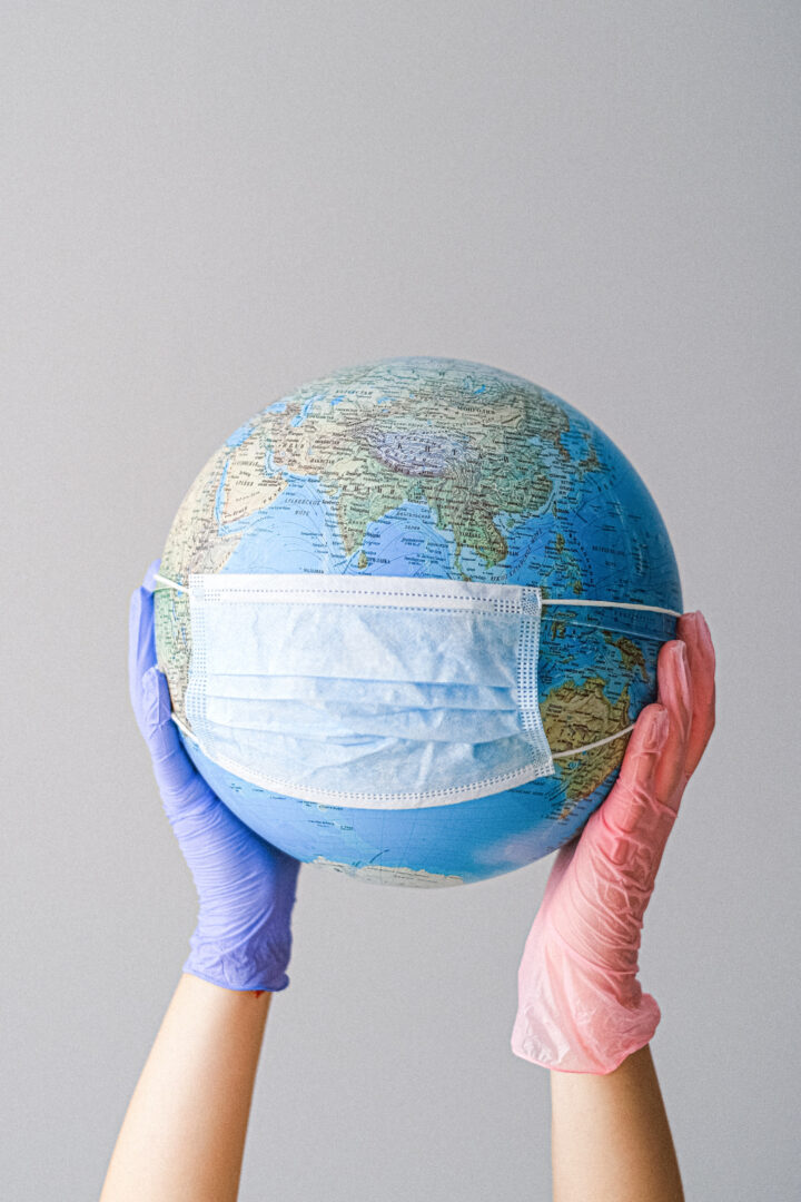 A view of hands holding a globe with a facemask