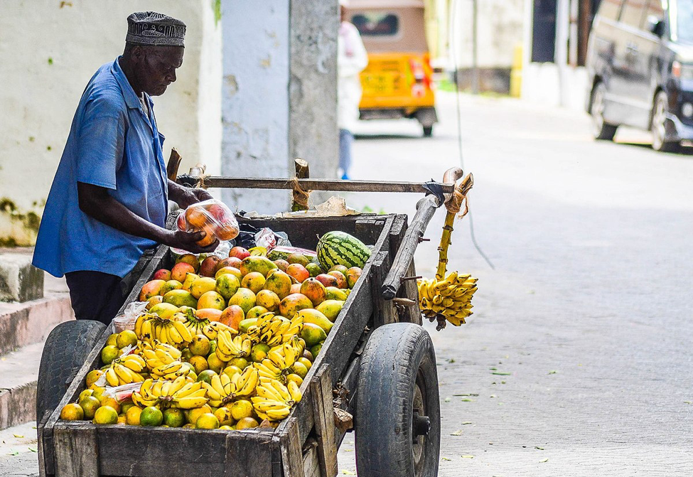 a man standing beside a cart filled with fruit