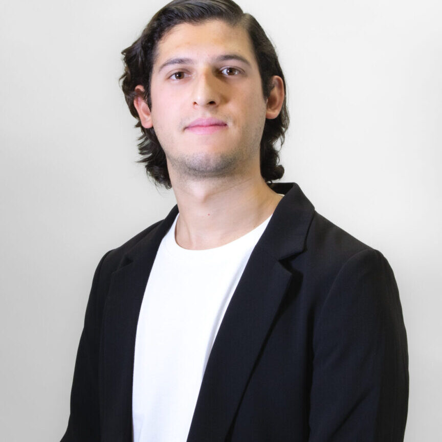 Young man in a black blazer and white shirt posing confidently.