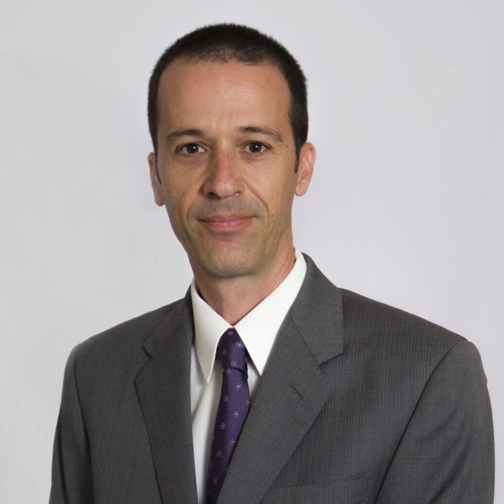 Professional man in a suit and tie against a plain background.
