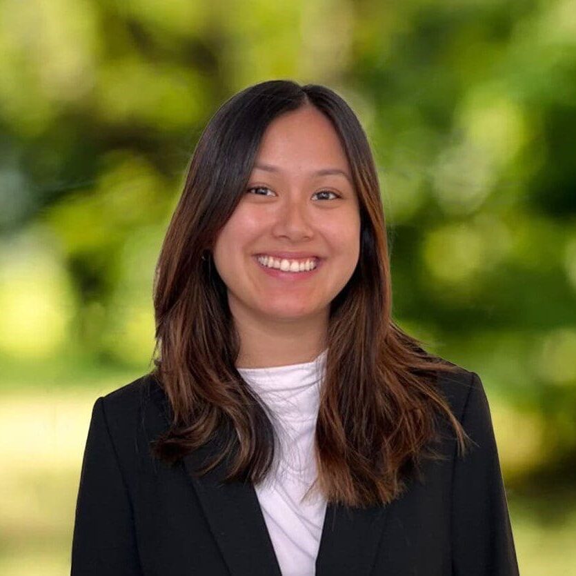 Professional woman smiling outdoors in business attire.