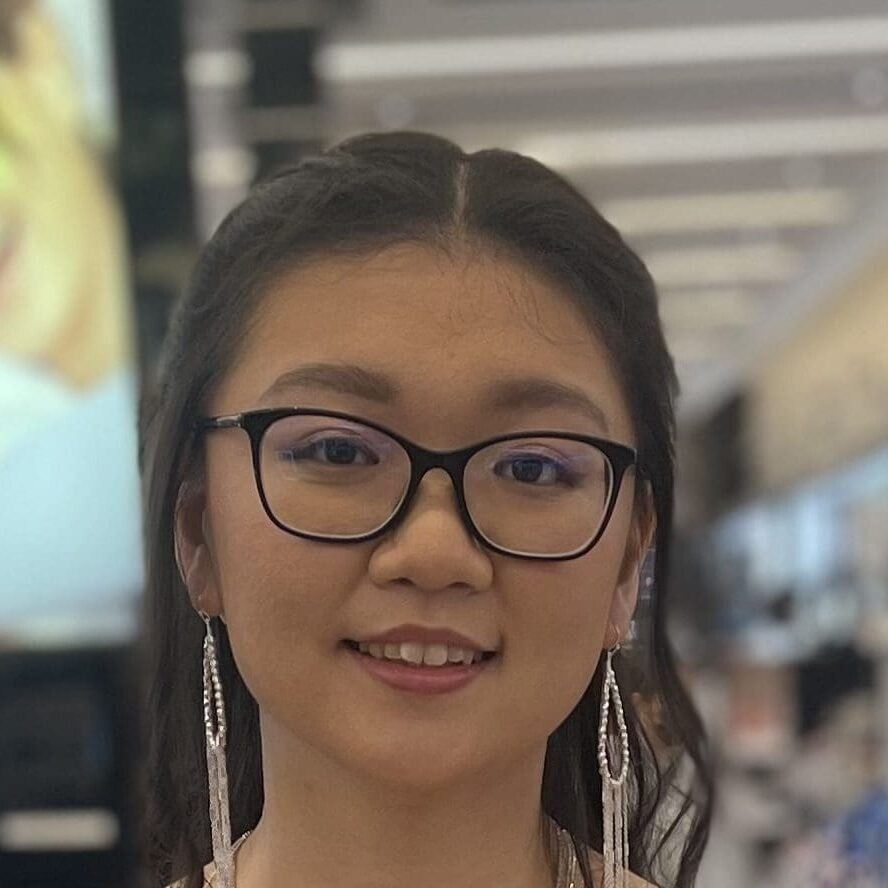 Young woman with glasses smiling indoors.