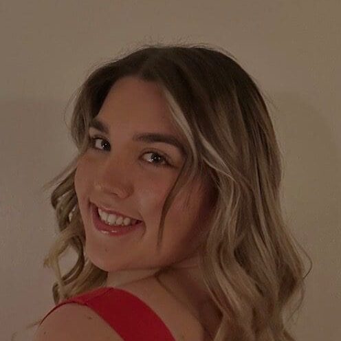 Young woman smiling with curled hair and red top.