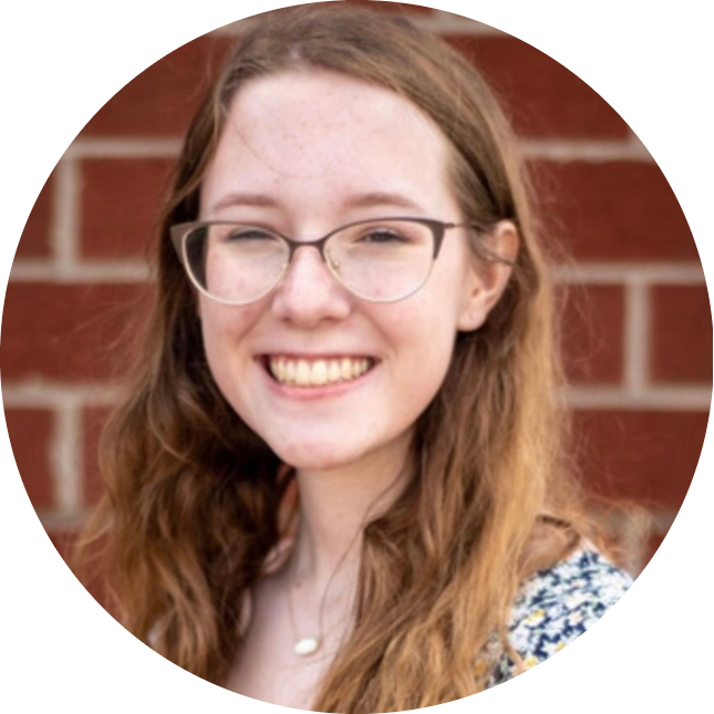 Young woman smiling in front of a brick wall.