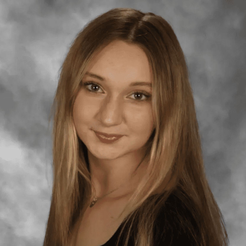 Portrait of a young woman with long blonde hair against a gray backdrop.