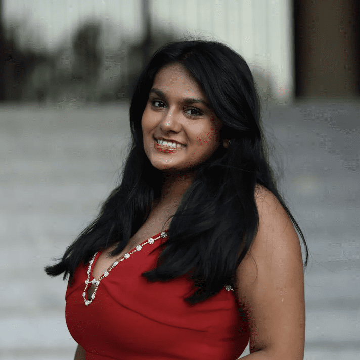 A smiling woman with long black hair wearing a red dress.