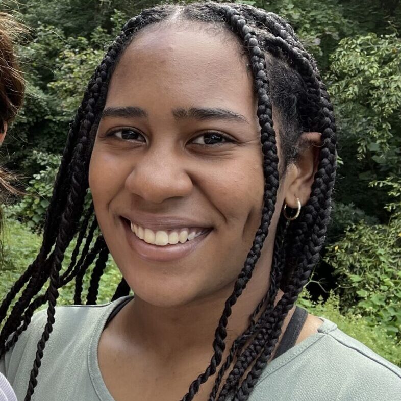 Smiling young woman with braided hair outdoors.