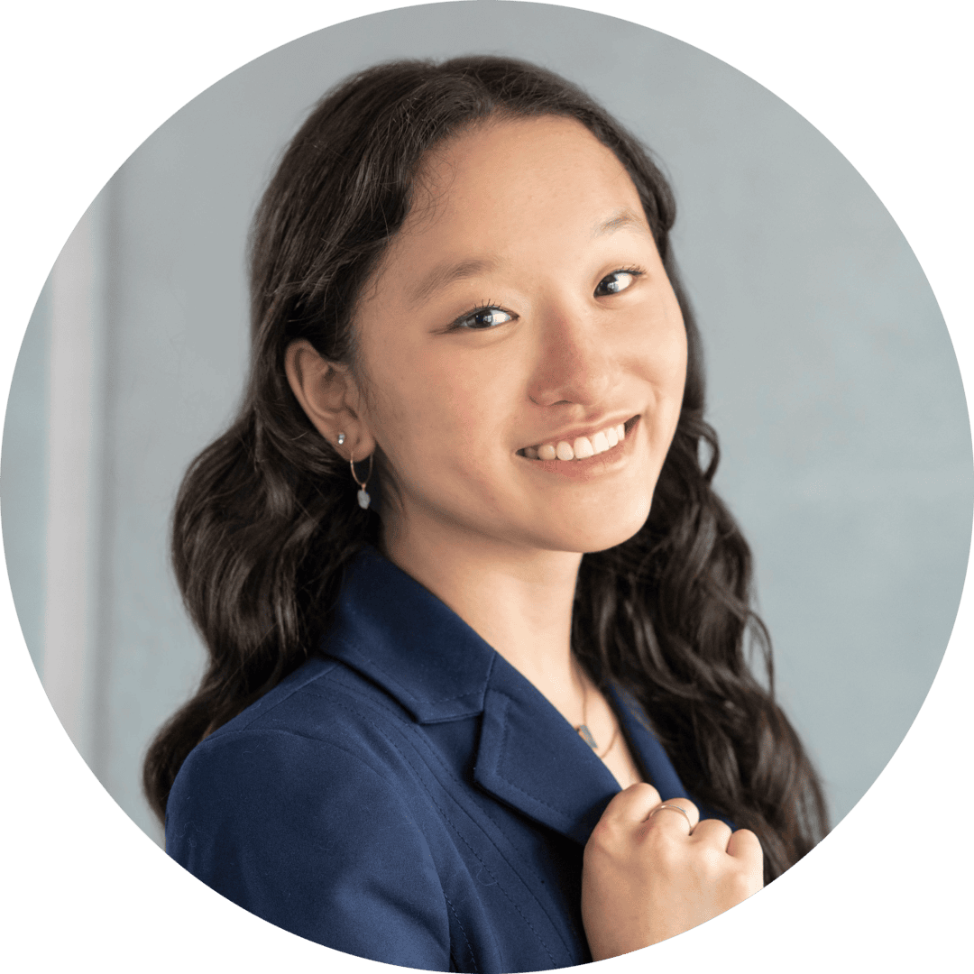 Professional portrait of a smiling young woman with wavy hair in a navy blazer.
