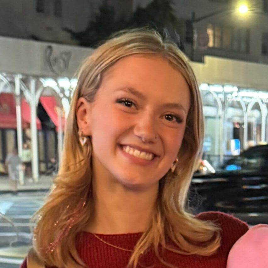 A smiling young woman with blonde hair outdoors at night.